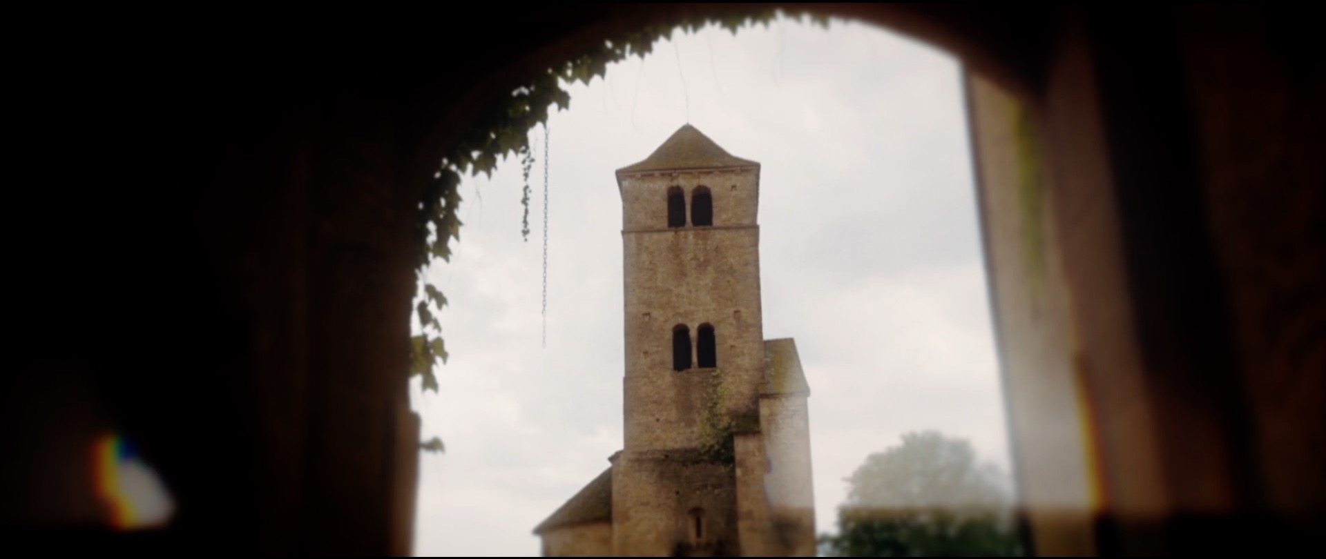 Clocher d'église vu depuis une arche végétale — extrait de film